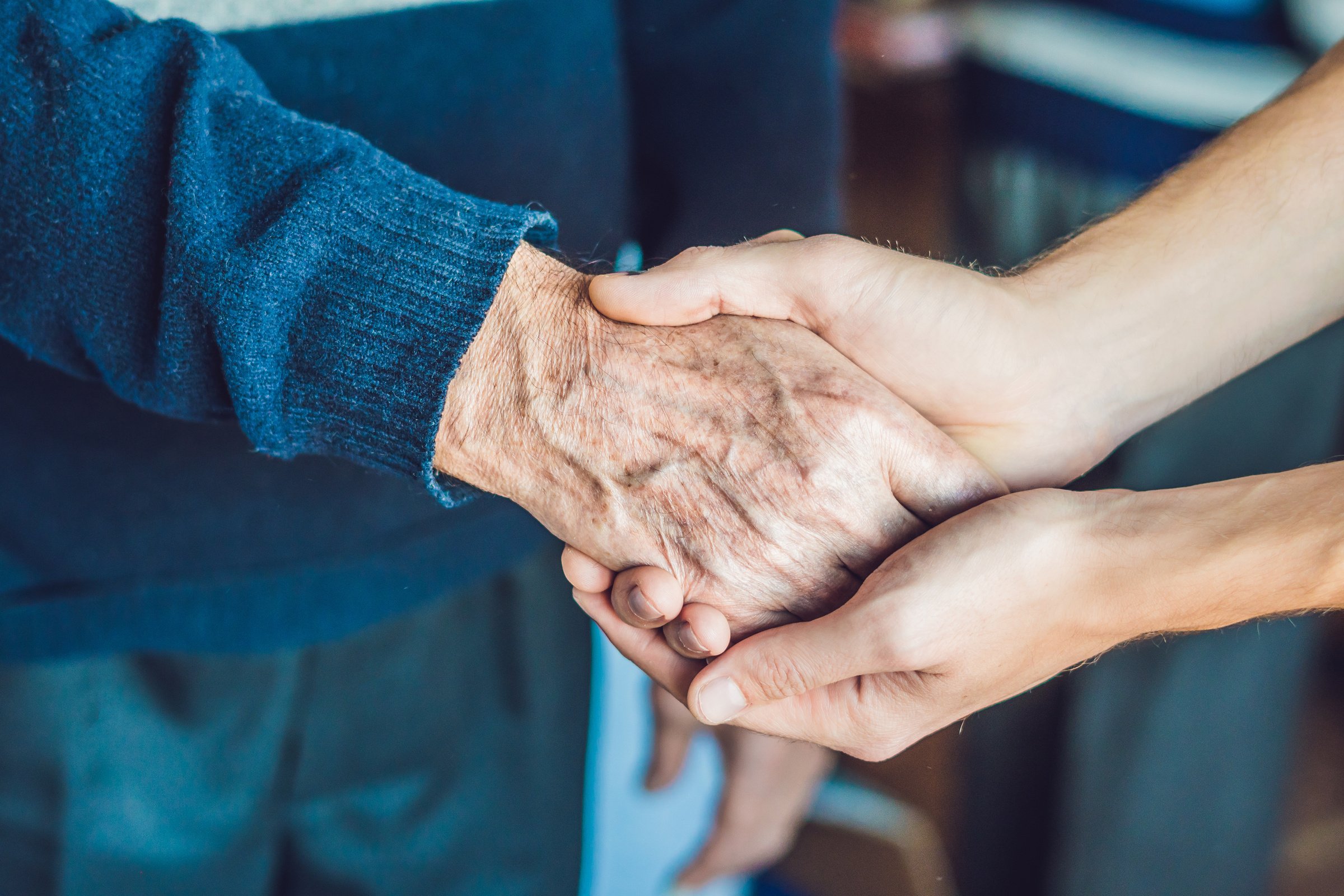 Hands of an Old Woman and a Young Man. Caring for the Elderly. Close up